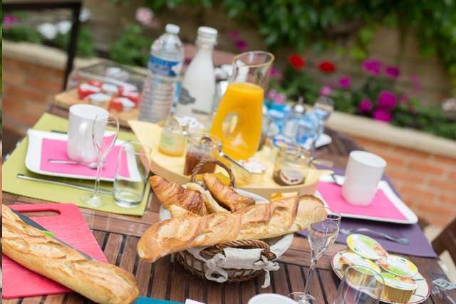 We see the breakfast table set up on the terrace with fresh products to enjoy while enjoying the sun and the garden.