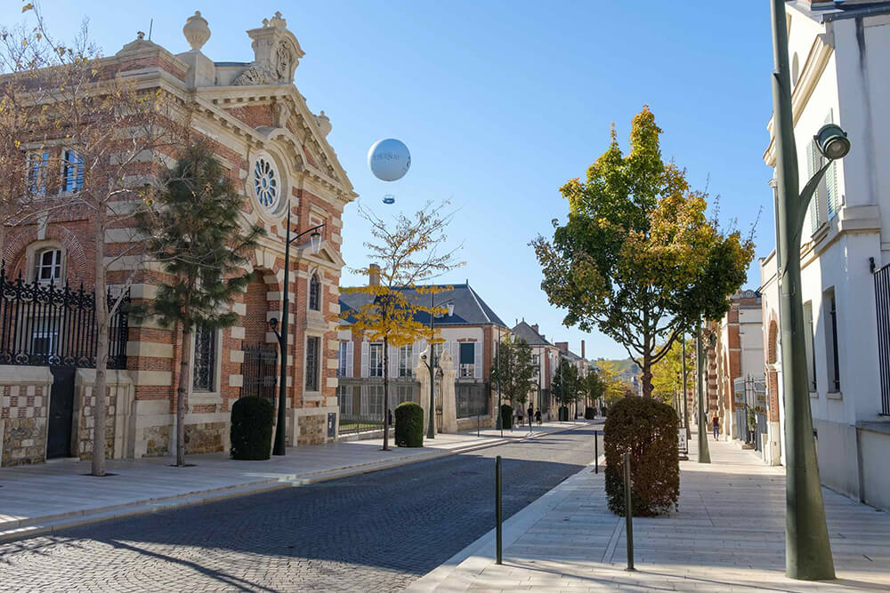 We see part of the Avenue de Champagne in Épernay with the tethered balloon in the sky in the distance behind the buildings