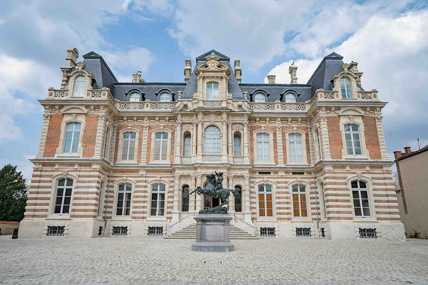 We see the facade of Château Perrier, the architecture of which is made up of a mixture of materials: brick, stone, slate and glass.