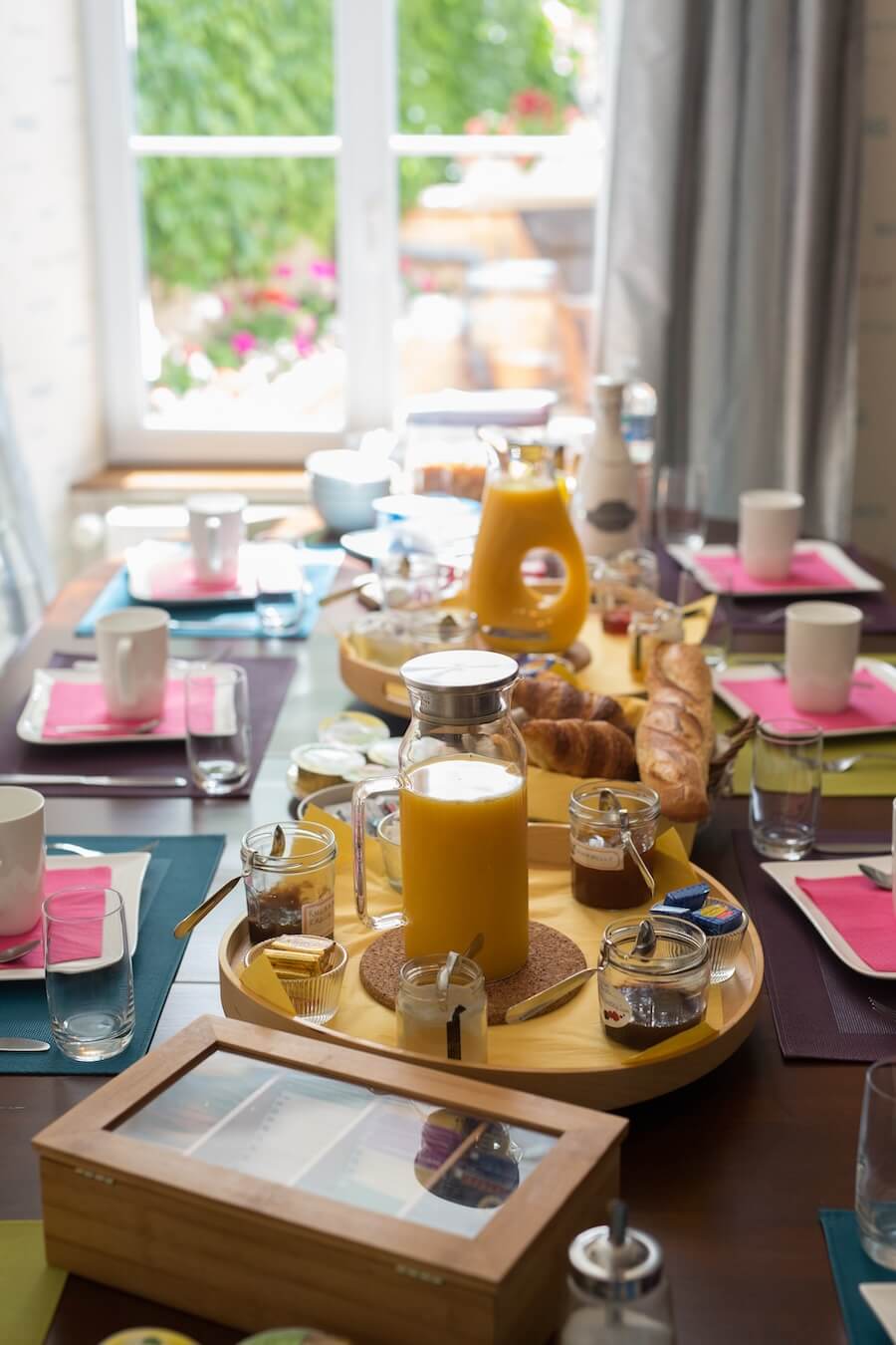 We see the breakfast table set in the Linterfaces dining room, garnished with pastries and baguettes from the baker, homemade products, fruits and fruit juices and many other sweet and savory things.